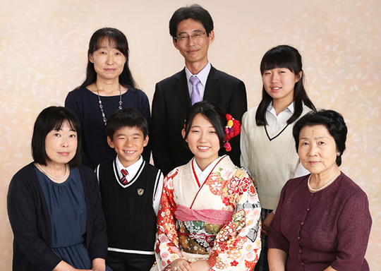 家族の記念写真。和装の成人式を迎えた女性を中心に、家族が集まっている温かな雰囲気の一枚。